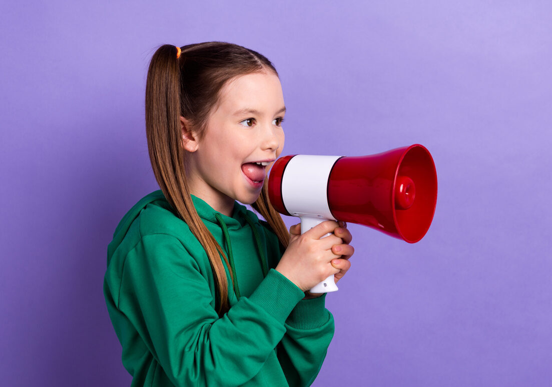 Ponnaripäinen tyttö huutaa megafoniin violettia taustaa vasten.